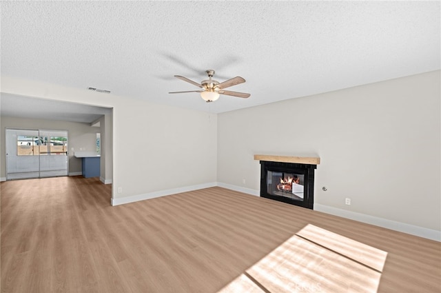 unfurnished living room with a textured ceiling, ceiling fan, and hardwood / wood-style flooring