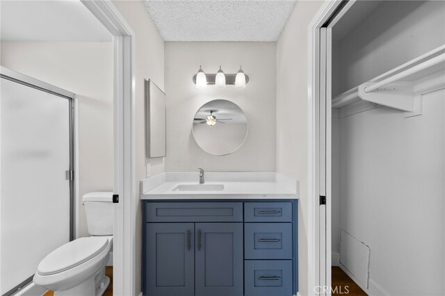 bathroom with toilet, vanity, ceiling fan, hardwood / wood-style flooring, and a textured ceiling