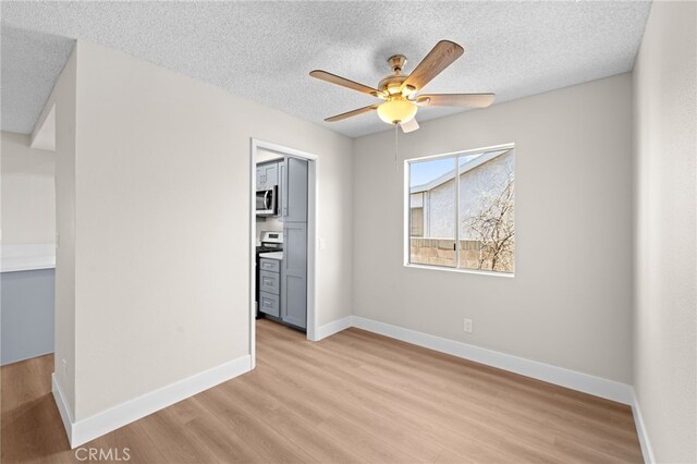 empty room with ceiling fan, a textured ceiling, and light hardwood / wood-style floors