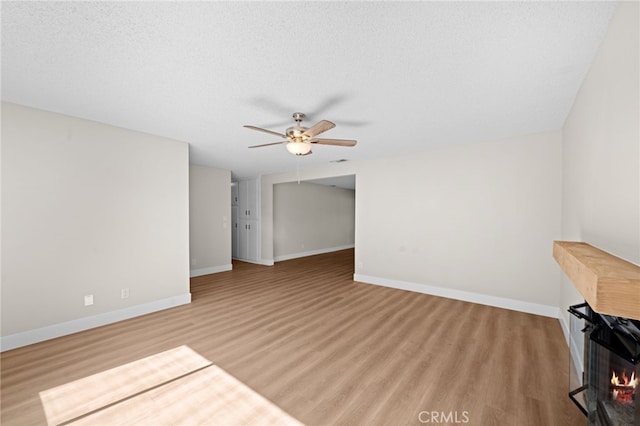 unfurnished living room featuring a textured ceiling, ceiling fan, and light hardwood / wood-style floors