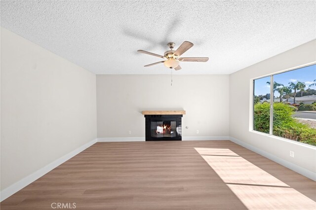 unfurnished living room with a textured ceiling, ceiling fan, and light hardwood / wood-style flooring