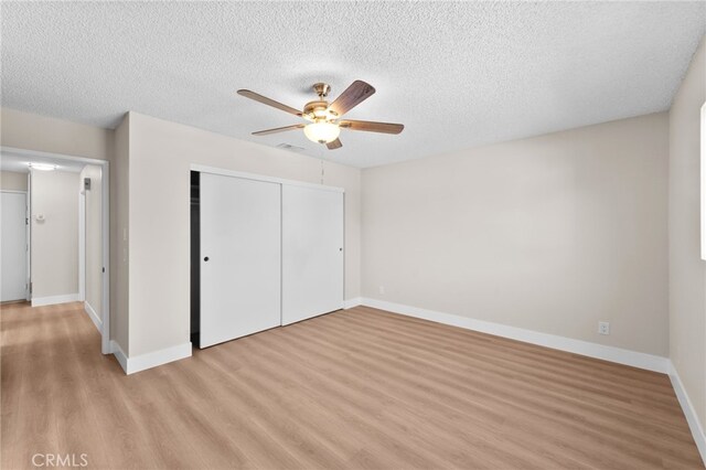 unfurnished bedroom with ceiling fan, a textured ceiling, a closet, and light hardwood / wood-style flooring