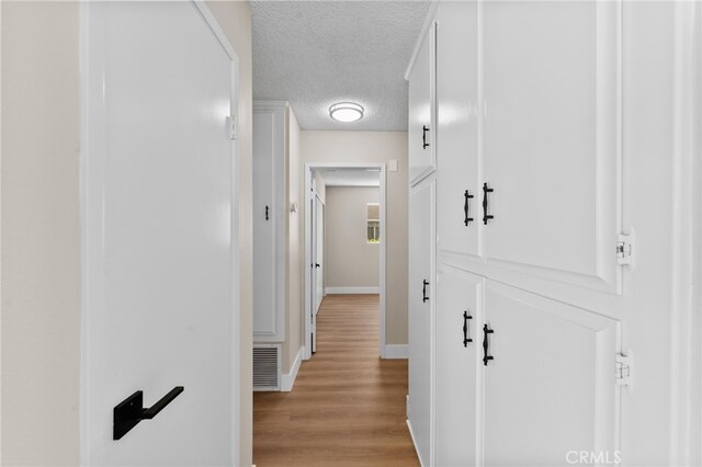 hall featuring a textured ceiling and light wood-type flooring