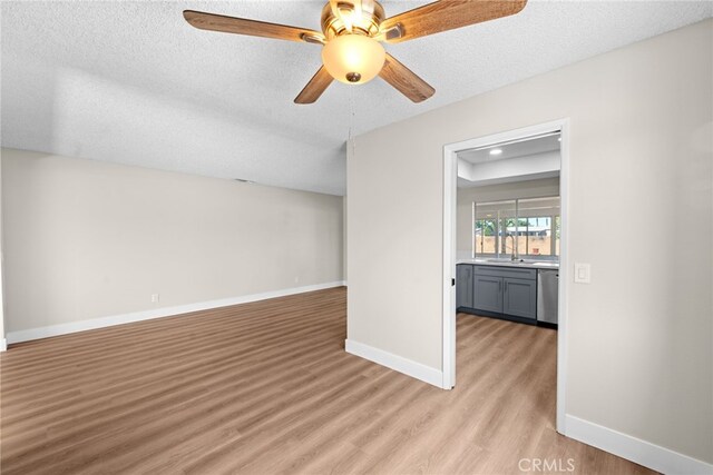 spare room with ceiling fan, sink, a textured ceiling, and light hardwood / wood-style flooring