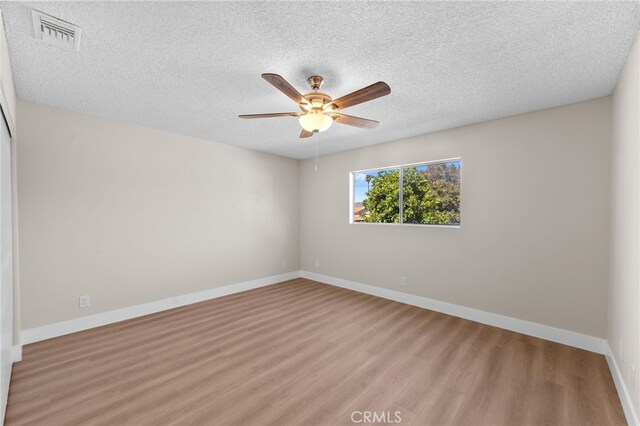 empty room featuring light wood-type flooring, ceiling fan, and a textured ceiling