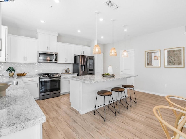 kitchen with tasteful backsplash, stainless steel appliances, white cabinetry, and a kitchen island