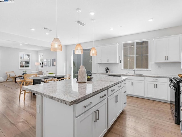 kitchen with white cabinetry, pendant lighting, black range with gas cooktop, and a center island