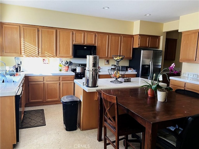 kitchen featuring tile counters, black appliances, and sink