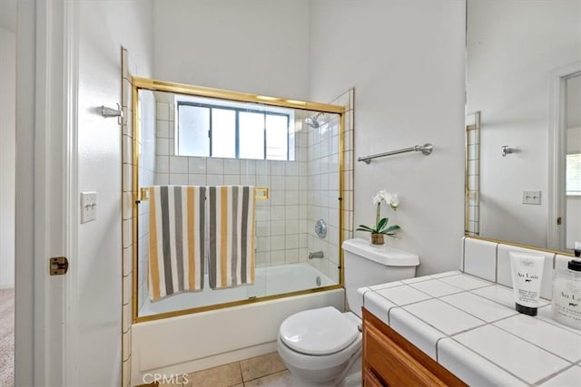 full bathroom featuring toilet, bath / shower combo with glass door, tile patterned floors, and vanity