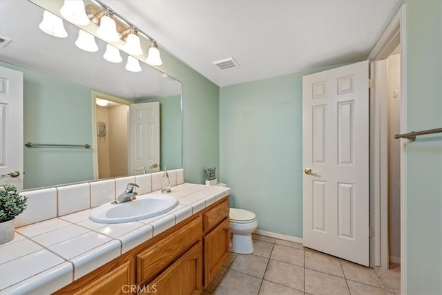 bathroom with toilet, vanity, and tile patterned floors