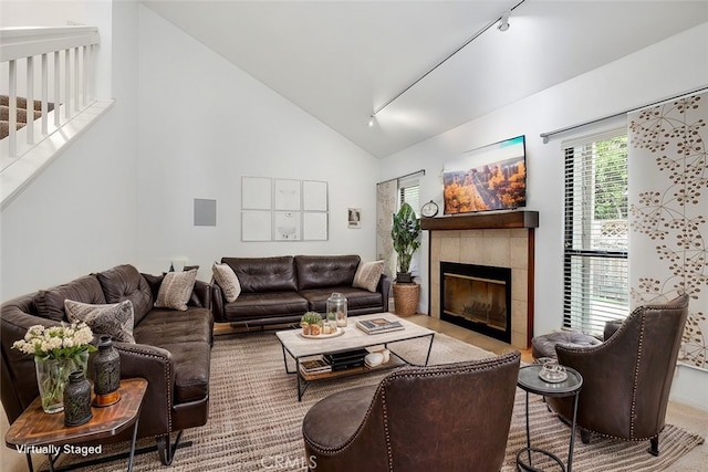 living room featuring high vaulted ceiling, rail lighting, and a tile fireplace