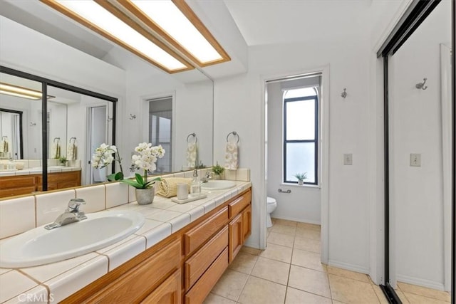 bathroom featuring toilet, lofted ceiling, tile patterned floors, and vanity