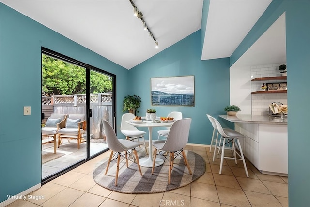 tiled dining area featuring track lighting and lofted ceiling