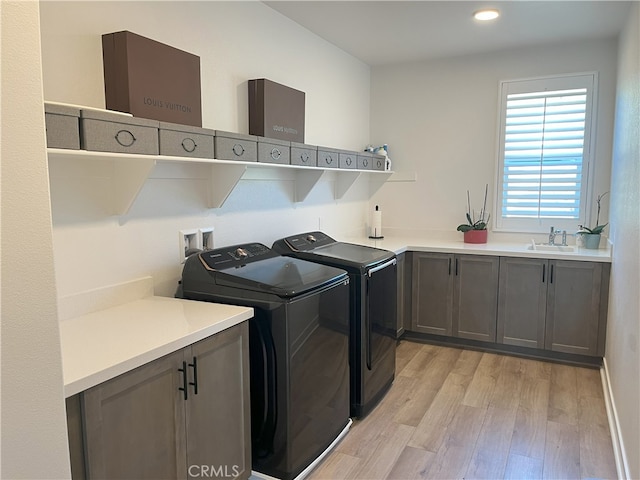 laundry room with light hardwood / wood-style floors, cabinets, sink, and washing machine and clothes dryer