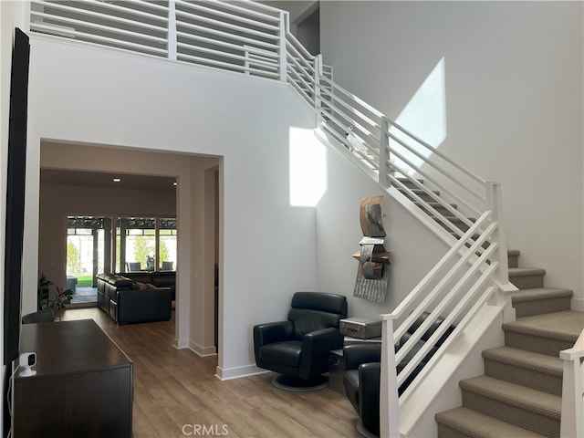 stairs with baseboards, a high ceiling, and wood finished floors