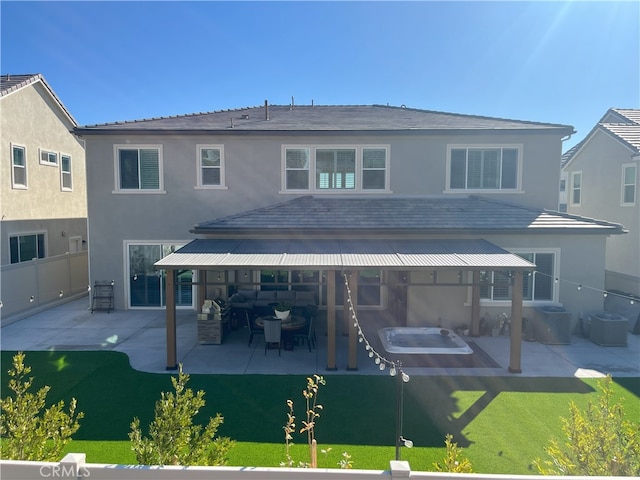 rear view of house with stucco siding, fence, and a patio