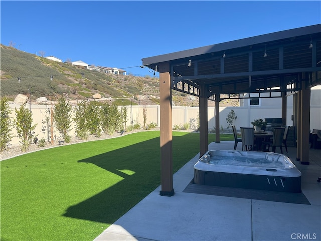 view of yard featuring a patio area, a hot tub, and a mountain view