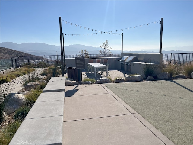 exterior space with exterior kitchen, a grill, fence, and a mountain view