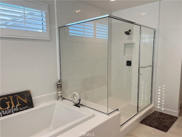 bathroom with a shower stall, a bath, and tile patterned floors