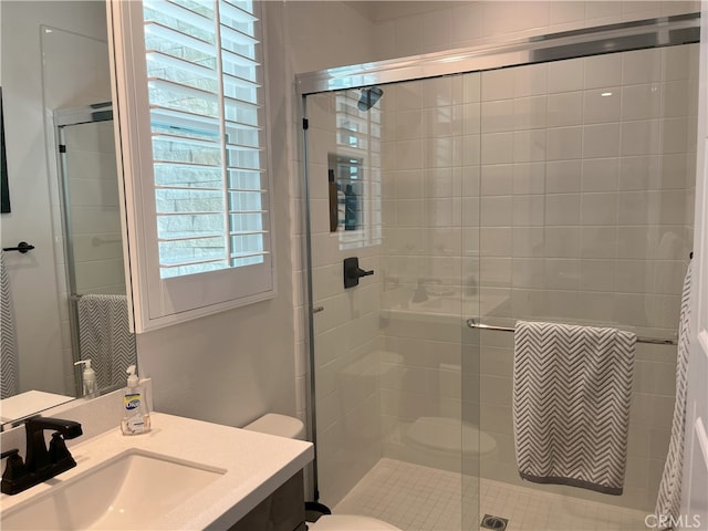 bathroom with a shower with shower door, toilet, and vanity