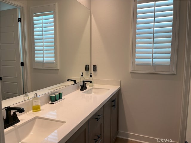 bathroom with double vanity, a sink, and baseboards