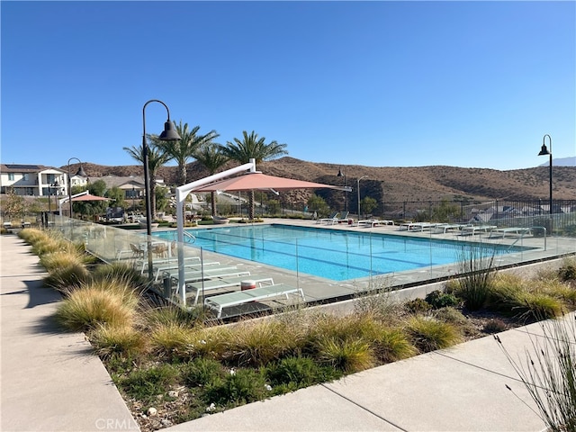 community pool featuring a patio area, fence, and a mountain view