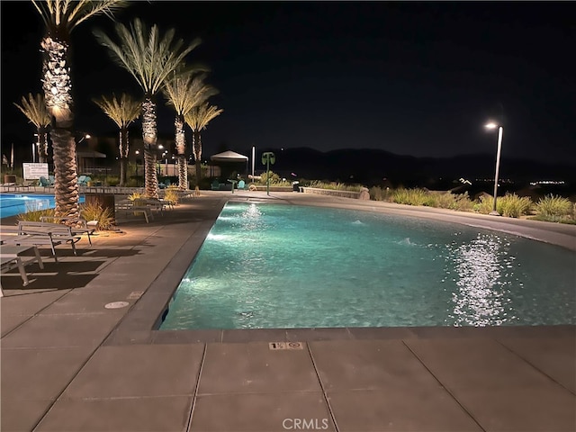 pool at twilight featuring a patio and a community pool