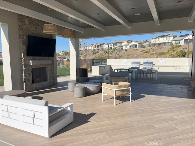 view of patio / terrace featuring exterior kitchen, an outdoor stone fireplace, and area for grilling