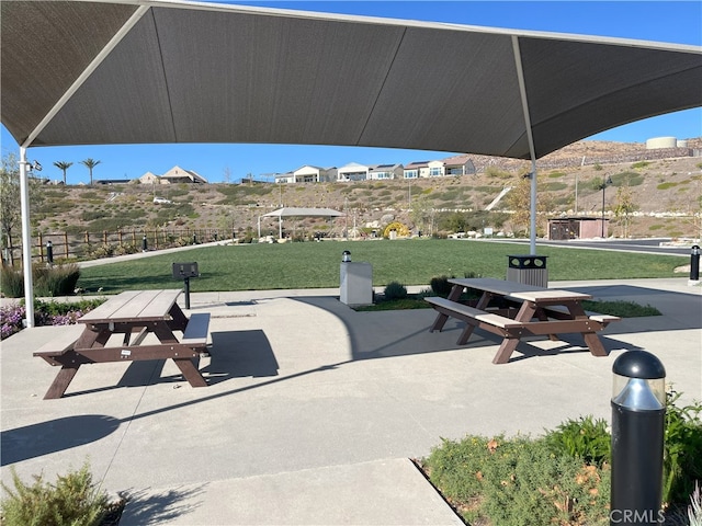 view of property's community featuring fence, a lawn, and a patio