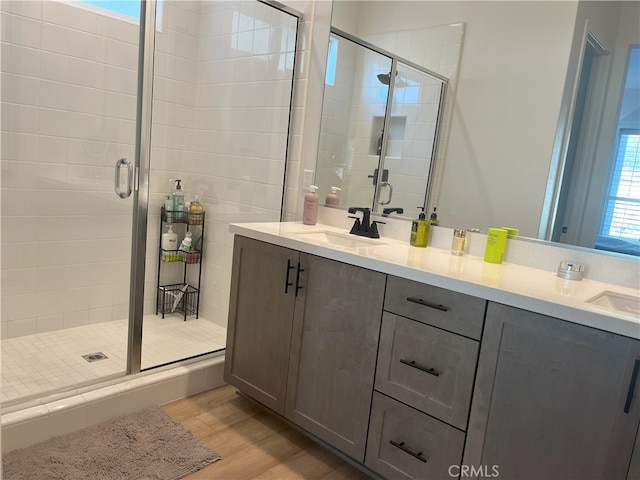 bathroom with hardwood / wood-style flooring, a shower with shower door, and vanity