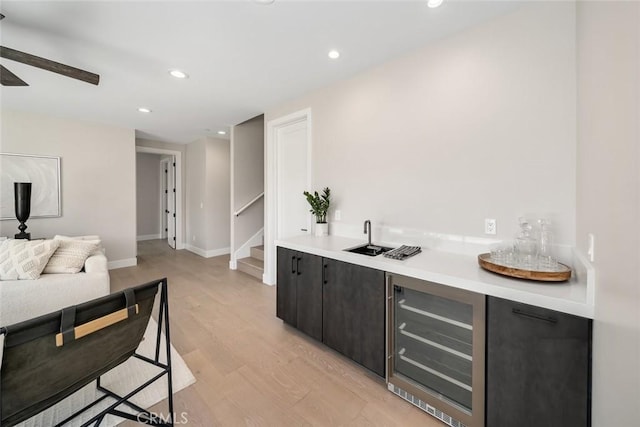 bar with wine cooler, light wood-type flooring, and sink