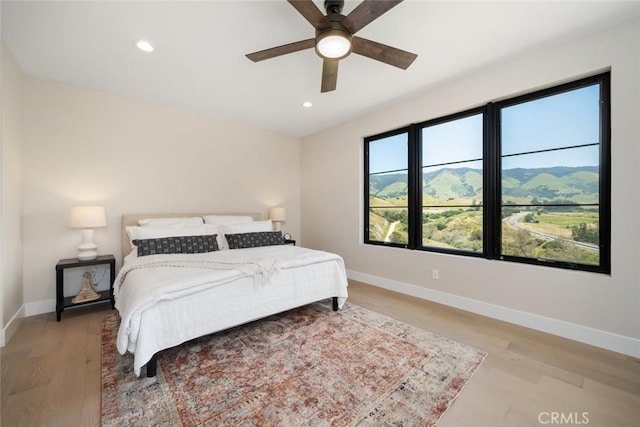 bedroom featuring ceiling fan, light hardwood / wood-style floors, and a mountain view