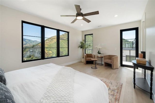 bedroom featuring ceiling fan, light hardwood / wood-style floors, and a mountain view