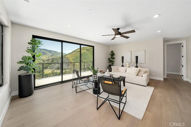 living room featuring ceiling fan, light hardwood / wood-style floors, and a mountain view