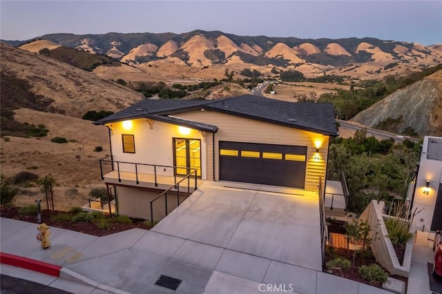 view of front of home with a garage, a mountain view, and a balcony