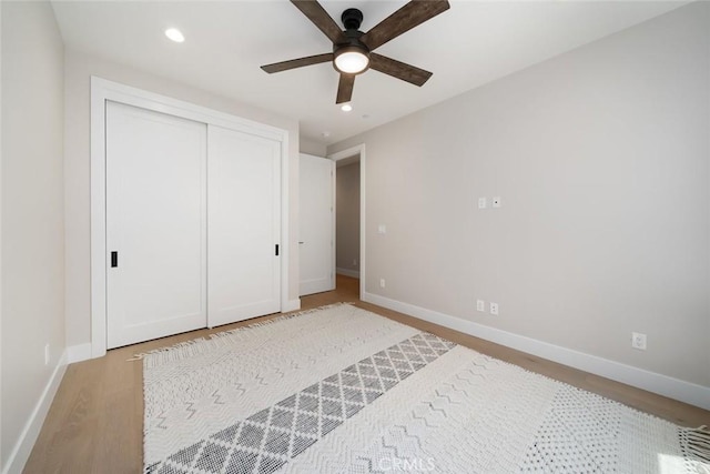 unfurnished bedroom with ceiling fan, a closet, and light hardwood / wood-style flooring