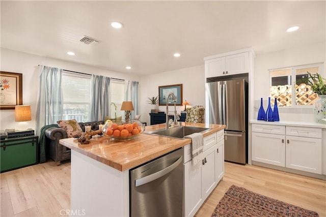 kitchen with sink, stainless steel appliances, an island with sink, and white cabinets