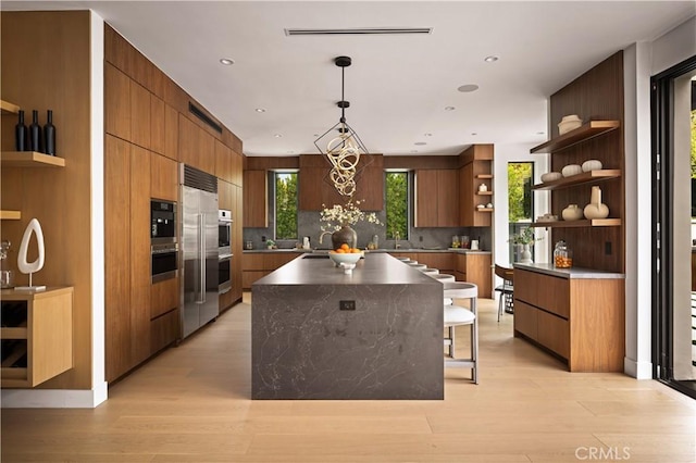 kitchen featuring light hardwood / wood-style floors, decorative backsplash, hanging light fixtures, a large island, and a notable chandelier