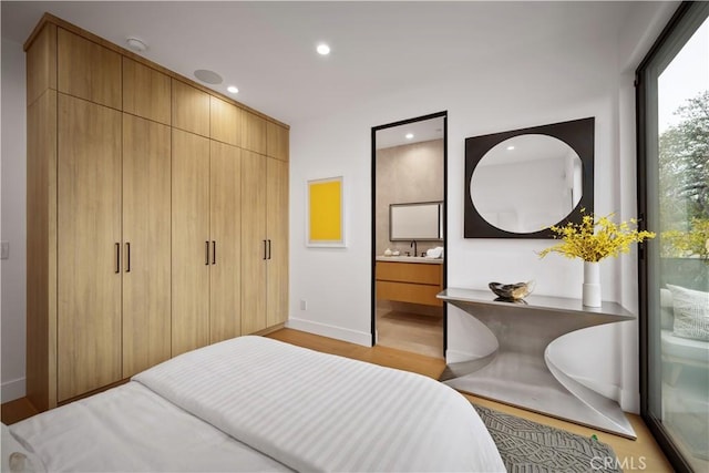 bedroom with ensuite bathroom and light wood-type flooring