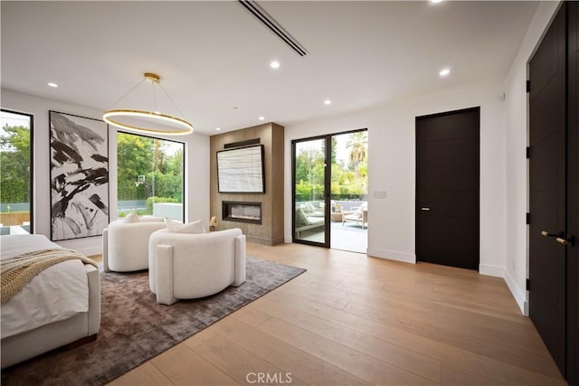 bedroom featuring access to outside, a fireplace, and light hardwood / wood-style flooring