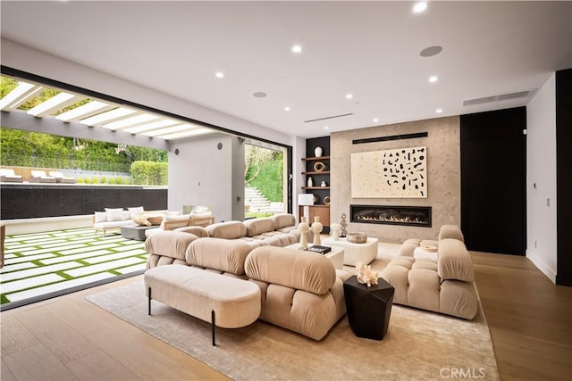 cinema room with built in shelves, light wood-type flooring, and a fireplace