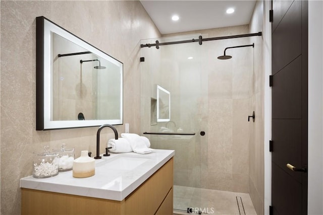 bathroom featuring a shower with shower door and vanity