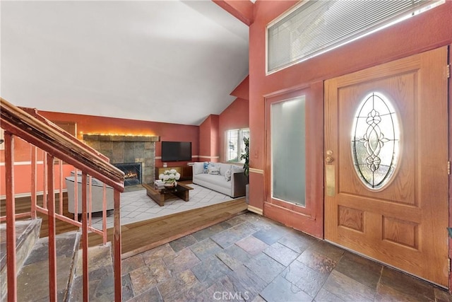 foyer entrance with lofted ceiling and a tile fireplace