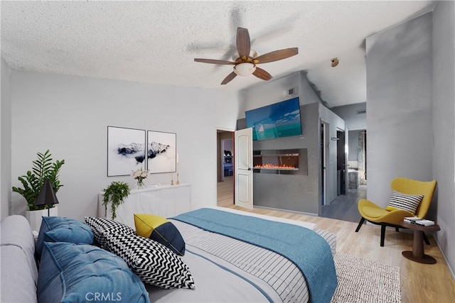 bedroom with ensuite bath, ceiling fan, a textured ceiling, and light hardwood / wood-style floors