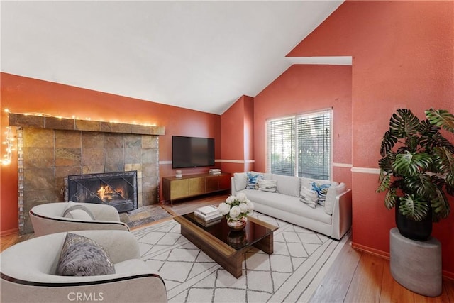 living room featuring light wood-type flooring, vaulted ceiling, and a fireplace