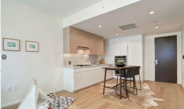 kitchen featuring gas stovetop, light hardwood / wood-style flooring, and tasteful backsplash