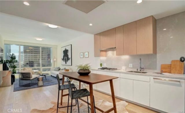 kitchen with light hardwood / wood-style floors, sink, decorative backsplash, white dishwasher, and gas cooktop