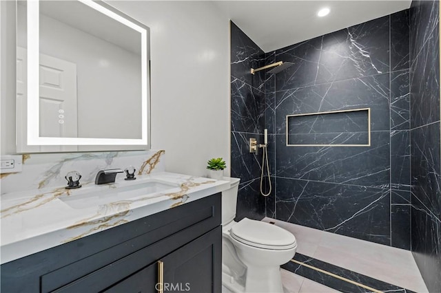 bathroom featuring tiled shower, vanity, toilet, and tile patterned flooring