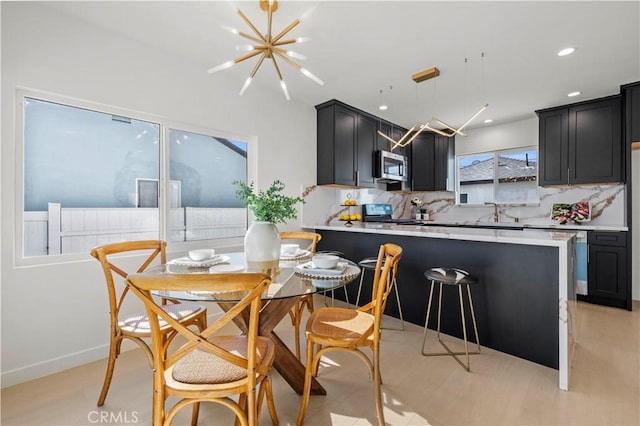 kitchen with an inviting chandelier, stainless steel appliances, backsplash, and hanging light fixtures