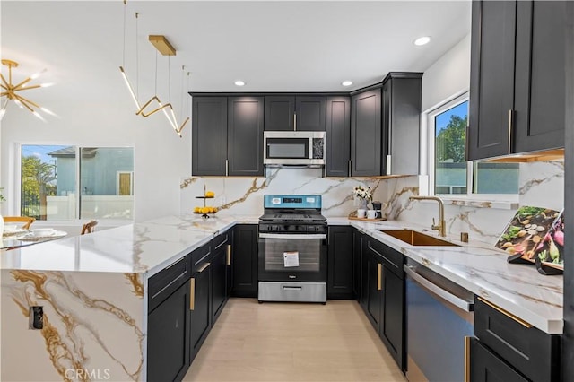 kitchen featuring hanging light fixtures, light stone countertops, sink, and stainless steel appliances